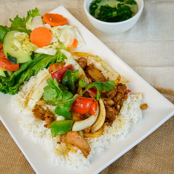Vietnamese chicken and rice dish with bell peppers, onions, cilantro, and a side salad with soup.